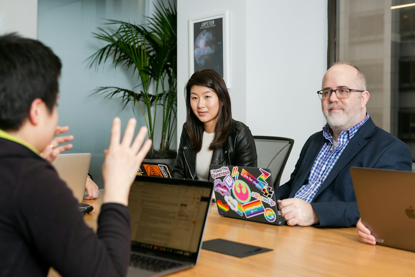 Business people in a meeting around a conference table with laptops.